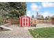 Red and white storage shed located in a landscaped backyard with mature trees and grass at 10525 W 18Th Ave, Lakewood, CO 80215