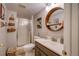 Well-lit bathroom with a glass-enclosed shower and a modern vanity with a round wood-framed mirror at 8229 Cottongrass Ct, Castle Pines, CO 80108