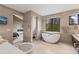 Bright bathroom featuring soaking tub, stone tile, and mountain views from the windows at 444 Glen Eagle Loop, Breckenridge, CO 80424