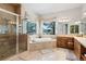 Luxurious bathroom with a glass shower, soaking tub, and double vanity with wood cabinets at 5329 Pinyon Jay Rd, Parker, CO 80134