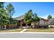 Charming home featuring a stone facade, well-manicured lawn, mature trees, and a welcoming walkway under a clear blue sky at 5329 Pinyon Jay Rd, Parker, CO 80134
