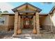 Inviting front entrance featuring stone columns, a wooden door, decorative planters, and a flagstone landing at 5329 Pinyon Jay Rd, Parker, CO 80134
