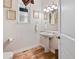 Charming powder room featuring a pedestal sink, decorative mirror, and wood flooring at 5329 Pinyon Jay Rd, Parker, CO 80134
