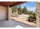 Covered back patio with brick columns and concrete pad leading to a spacious landscaped backyard at 7370 S Catawba Way, Aurora, CO 80016