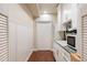 Hallway with wainscoting, wood floors, white cabinets, and a sink with a microwave at 7370 S Catawba Way, Aurora, CO 80016