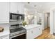 Bright kitchen featuring white cabinets, stainless steel appliances, and a quartz countertop with pendant lighting at 1047 Uinta Way, Denver, CO 80230