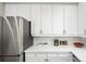 Modern kitchen featuring stainless steel refrigerator, white cabinets, quartz countertop, and a herringbone backsplash at 1047 Uinta Way, Denver, CO 80230