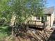 Backyard view showing a small wooden deck with stairs, garden beds, and mature trees at 21444 E Lehigh Ave, Aurora, CO 80013