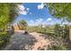 Large backyard with a stone patio and a wooden fence, surrounded by lush landscaping and clear blue skies at 5400 S Quail Way, Littleton, CO 80127