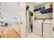 Efficient laundry room with front-load washer and dryer, shelving with decor baskets, and a hanging ironing board at 5400 S Quail Way, Littleton, CO 80127