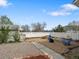 Backyard featuring a gravel area, blue chairs, fire pit, white fence, shed, and green foliage at 19093 W 61St Pl, Golden, CO 80403