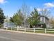 Charming two-story home with a well-maintained lawn, white picket fence, and mature trees at 19093 W 61St Pl, Golden, CO 80403