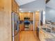Charming kitchen featuring wood cabinets, stainless steel appliances, granite counters, and wood floors at 19093 W 61St Pl, Golden, CO 80403