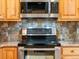 Stainless steel range, microwave, and granite counters with mosaic tile backsplash in a modern kitchen at 19093 W 61St Pl, Golden, CO 80403