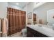 Cozy bathroom features a shower with a decorative curtain, a toilet and dark-stained vanity at 12677 Fisher Dr, Englewood, CO 80112