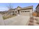 Home featuring neutral siding, stone accents, a two-car garage, and professional landscaping at 12677 Fisher Dr, Englewood, CO 80112