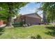 Brick home's backyard featuring a tree, green turf, and rock landscaping at 8893 W Harvard Dr, Lakewood, CO 80227
