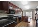 Bright kitchen featuring hardwood flooring, dark wood cabinetry, black appliances, and sliding glass door to backyard at 8893 W Harvard Dr, Lakewood, CO 80227