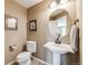 Cozy powder room featuring a pedestal sink, round mirror, and neutral tones at 26764 E Canyon Ave, Aurora, CO 80016