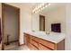 Spacious bathroom featuring double sinks with wood cabinets, an illuminated mirror, and neutral walls at 4094 S Lisbon Way, Aurora, CO 80013