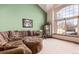 Comfortable living room with plush sectional, patterned ottoman, green wall, and a large window at 4094 S Lisbon Way, Aurora, CO 80013