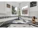 Modern kitchen sink area showcasing granite counters, stylish backsplash, and natural light at 11411 W Cooper Dr, Littleton, CO 80127