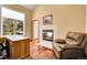 Well-lit office space featuring a fireplace, a large window with backyard views, and a wooden desk at 11411 W Cooper Dr, Littleton, CO 80127
