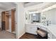 Bright bathroom with double mirrors, vanity seating, and a walk-in closet entrance at 2317 Wynterbrook Dr, Highlands Ranch, CO 80126