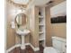 Quaint bathroom with pedestal sink, decorative mirror, patterned wallpaper, and built in shelves at 2317 Wynterbrook Dr, Highlands Ranch, CO 80126