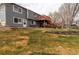 Backyard view of a house with a wooden deck, lawn area, and stone retaining wall at 5283 E 131St Dr, Thornton, CO 80241