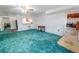Cozy living room with teal carpet, an open snack bar area, and a doorway to unfinished basement at 5283 E 131St Dr, Thornton, CO 80241