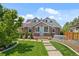 Charming stone home with blue door, dormer windows, American flag, and a well-manicured lawn at 895 Nile Ct, Golden, CO 80401