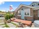 Charming stone house with a blue door and a wooden porch surrounded by green plants and an American flag at 895 Nile Ct, Golden, CO 80401