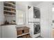 Bright laundry room features a stacked washer and dryer, shiplap walls, and storage shelves with decor at 895 Nile Ct, Golden, CO 80401