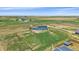 Aerial view of the property featuring a blue house, outbuildings, and fenced paddocks at 32800 E 137Th Way, Brighton, CO 80603