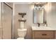 Modern bathroom features tiled shower, floating shelves, and wood vanity with updated mirror at 10117 Wyandott N Cir, Thornton, CO 80260