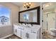 Bathroom featuring double sinks, white cabinets, and large framed mirror at 10117 Wyandott N Cir, Thornton, CO 80260