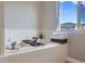 Relaxing soaking tub with white tiled surround and serene window view at 10117 Wyandott N Cir, Thornton, CO 80260