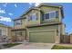 Two-story green home featuring a two-car garage, stone accents, and well-maintained landscaping at 10117 Wyandott N Cir, Thornton, CO 80260
