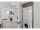 A white, stacked washer and dryer inside of a laundry closet, with the living room in the background at 4100 Albion St # 314, Denver, CO 80216