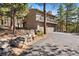 Exterior of home with a balcony, two-car garage, stone retaining wall, driveway, and mature trees at 2386 Daisy Ln, Golden, CO 80401