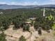 Aerial view of a home with a red barn, horse pasture, and a dense forest backdrop at 20125 Indi Dr, Monument, CO 80132