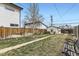 A fully fenced backyard with a detached garage, green grass, and a small tree at 2886 S Acoma St, Englewood, CO 80110