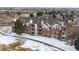 Aerial view of the brick building with multiple balconies overlooking snow-covered grounds and mature trees at 2897 W Riverwalk Cir # 204, Littleton, CO 80123