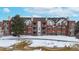 A brick building with well-maintained balconies and decorative accents overlooks a snow-covered landscape with mature trees at 2897 W Riverwalk Cir # 204, Littleton, CO 80123