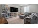 Spacious living room with gray sectional sofa, white shelves and a large TV for relaxing and entertaining at 1408 Brookfield Pl, Lafayette, CO 80026