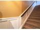Carpeted staircase with white trim and a wooden handrail, leading to the upper level of the home at 2305 Dogwood Cir, Erie, CO 80516