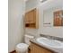 A well-lit powder room featuring a toilet, a vanity with a sink, and simple cabinetry at 15925 E 13Th Ave, Aurora, CO 80011