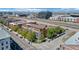 An aerial view displays modern condominiums with balconies and street parking, set against a backdrop of cityscape and mountains at 3295 Blake St # 301, Denver, CO 80205