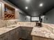 Basement bar features stone counters and is located adjacent to movie theater area at 5708 Wetland Loop, Frederick, CO 80504